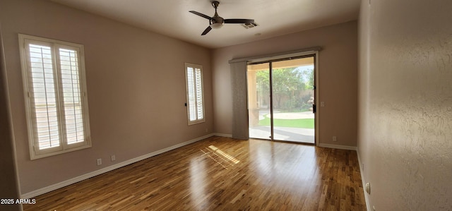 unfurnished room with ceiling fan, wood finished floors, visible vents, and baseboards