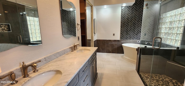 full bath with double vanity, a soaking tub, tile walls, and a sink