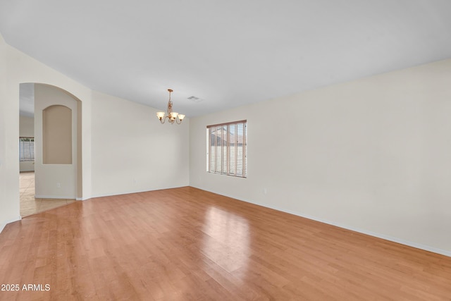 30215 N Joshua Tree Dr, Florence, AZ 85132 - empty room featuring light wood-style floors, a chandelier, and arched walkways