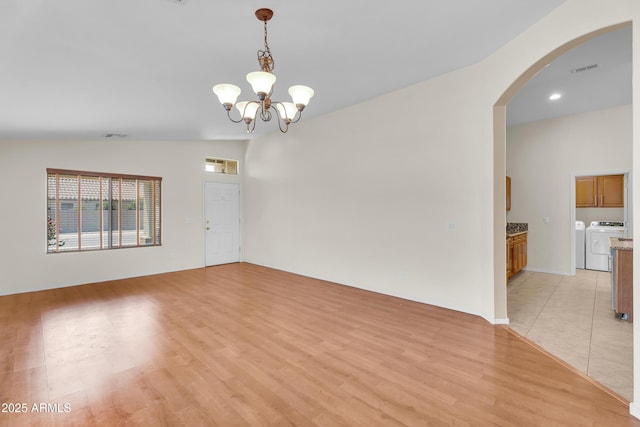 30215 N Joshua Tree Dr, Florence, AZ 85132 - spare room with washer and dryer, arched walkways, light wood finished floors, a chandelier, and lofted ceiling