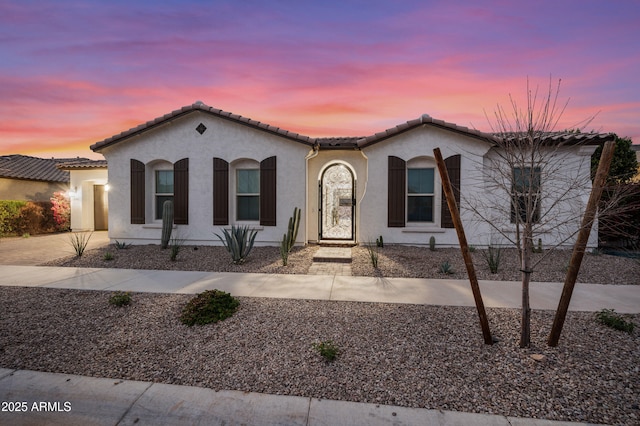 mediterranean / spanish house with a tile roof, driveway, and stucco siding