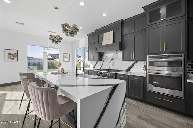 kitchen featuring a breakfast bar area, a center island with sink, stainless steel appliances, decorative backsplash, and a sink