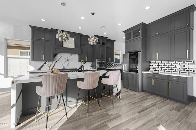 kitchen featuring a wealth of natural light, decorative backsplash, appliances with stainless steel finishes, and a kitchen island with sink