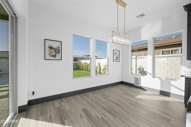 unfurnished dining area with light wood finished floors, visible vents, and baseboards