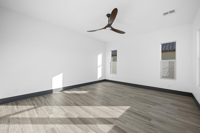 unfurnished room featuring baseboards, wood finished floors, visible vents, and ceiling fan