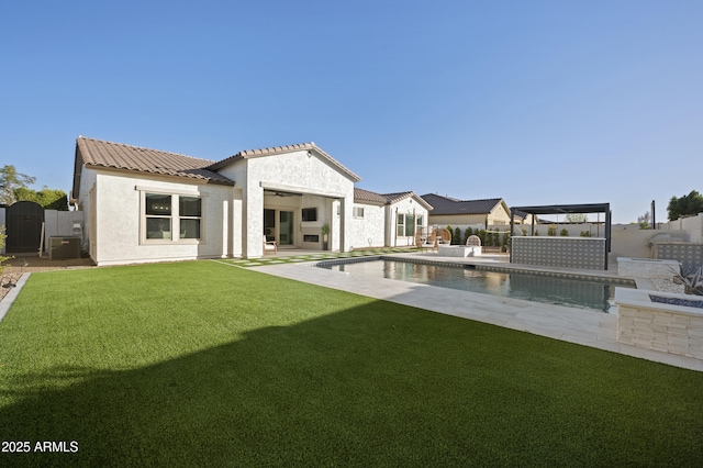 back of property featuring a yard, stucco siding, a tile roof, and a fenced backyard