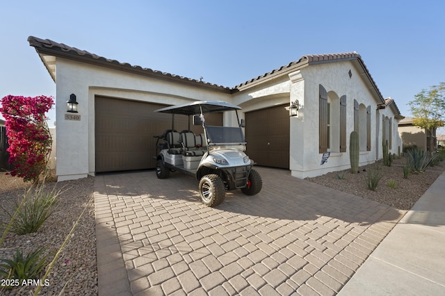 view of home's exterior featuring decorative driveway, a tile roof, an attached garage, and stucco siding