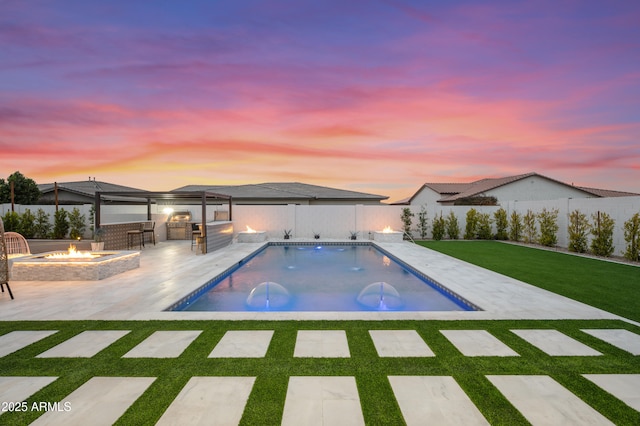 view of swimming pool featuring a patio, an outdoor kitchen, an outdoor fire pit, a fenced backyard, and a lawn