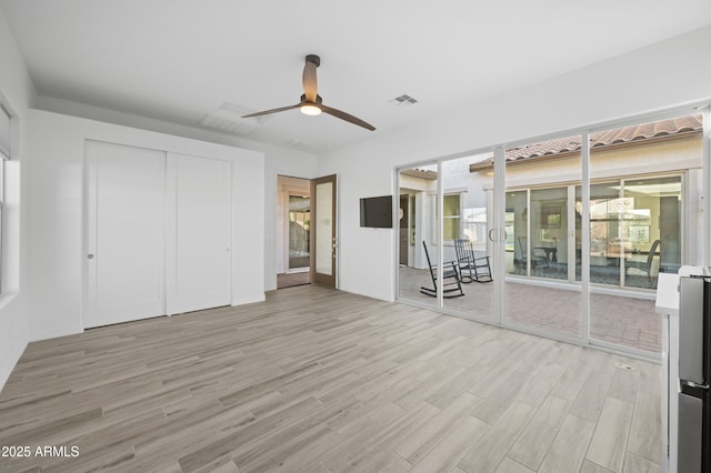 unfurnished bedroom featuring ceiling fan, visible vents, a closet, and light wood-style flooring