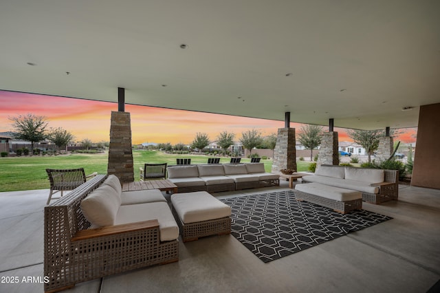 patio terrace at dusk featuring a lawn and an outdoor hangout area