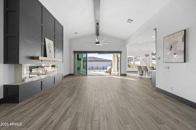 unfurnished living room featuring beamed ceiling, wood finished floors, visible vents, and a healthy amount of sunlight