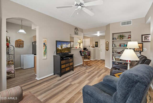 living area featuring a ceiling fan, light carpet, and baseboards