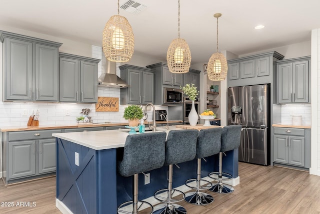 kitchen with visible vents, gray cabinetry, stainless steel appliances, and wall chimney exhaust hood