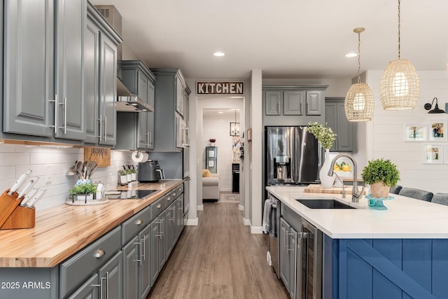 kitchen featuring beverage cooler, butcher block counters, gray cabinets, wood finished floors, and a sink