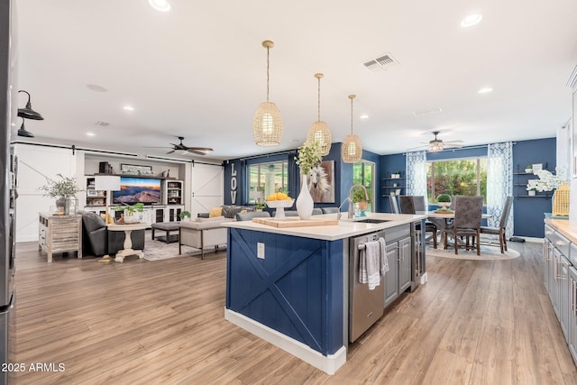 kitchen featuring open floor plan, dishwasher, light countertops, a barn door, and a sink