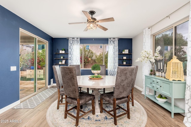 dining space featuring baseboards, light wood-style flooring, and a ceiling fan