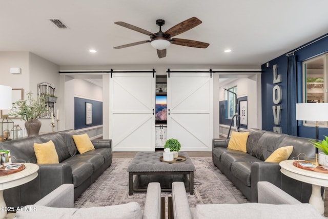 living room with recessed lighting, a barn door, visible vents, and wood finished floors