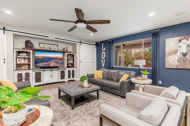 living area featuring a barn door, wood finished floors, a ceiling fan, and recessed lighting