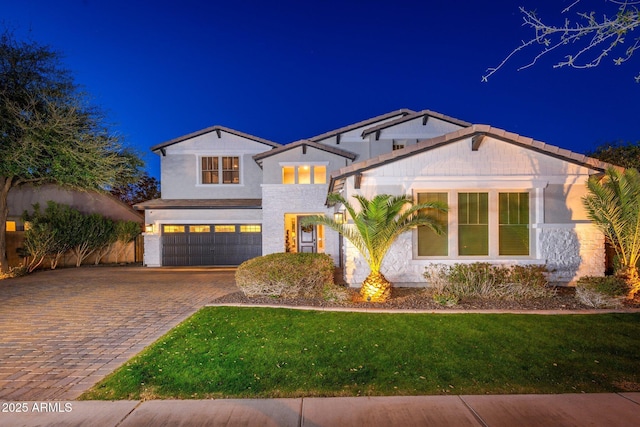 view of front of home featuring a lawn, decorative driveway, a garage, and stucco siding