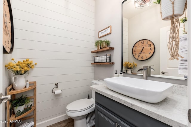 bathroom with toilet, vanity, and wood finished floors