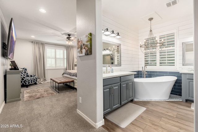 ensuite bathroom with visible vents, connected bathroom, vanity, and a freestanding tub