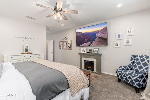 carpeted bedroom featuring baseboards, visible vents, recessed lighting, a warm lit fireplace, and ceiling fan