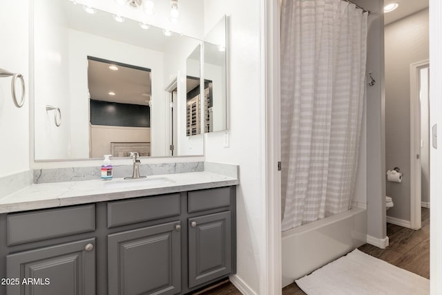 bathroom with baseboards, toilet, wood finished floors, shower / bath combination with curtain, and vanity