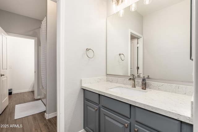 full bathroom with vanity, a shower with shower curtain, wood finished floors, and baseboards