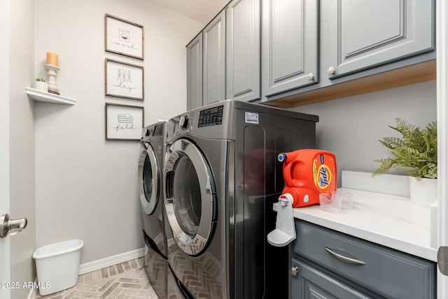 washroom featuring brick floor, cabinet space, independent washer and dryer, and baseboards