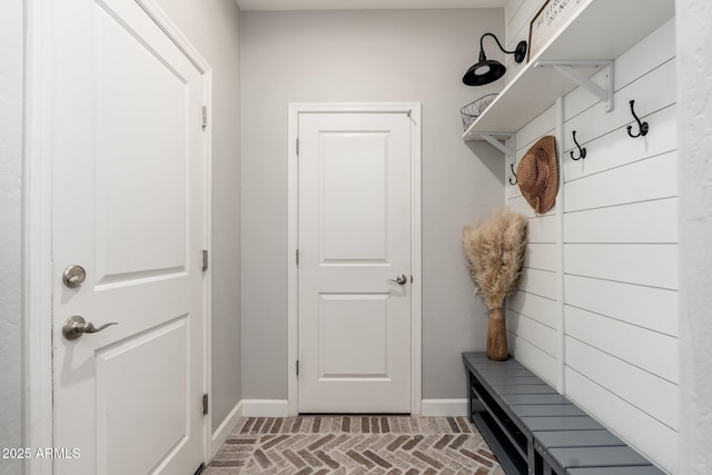 mudroom featuring brick floor and baseboards