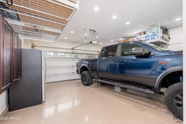 garage featuring recessed lighting, a garage door opener, and freestanding refrigerator