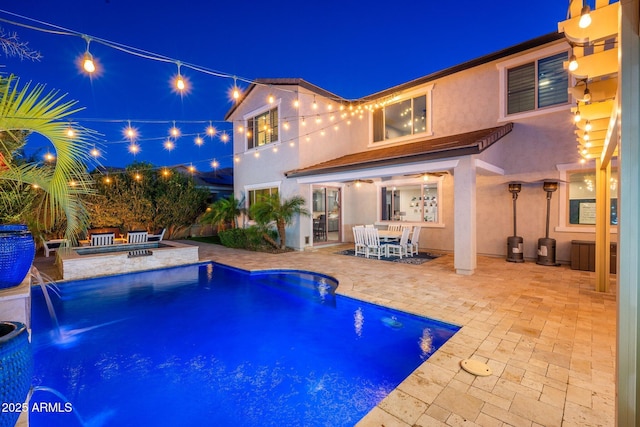 pool at twilight with a patio area, outdoor dining space, an outdoor pool, and a fire pit