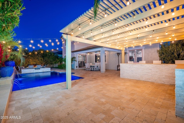 pool at night featuring outdoor dining space, an outdoor pool, and a patio