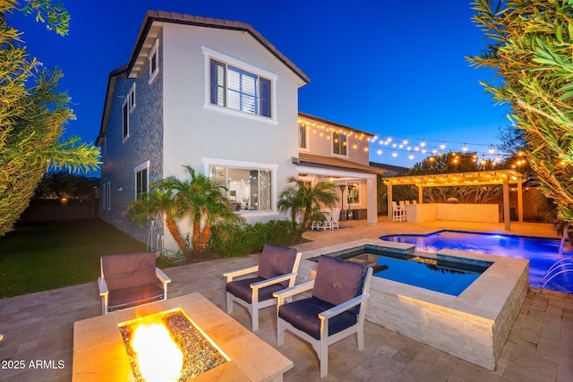 rear view of house featuring stucco siding, a fire pit, an outdoor pool, an in ground hot tub, and a patio area