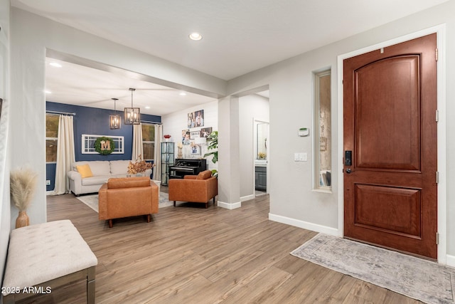 entryway with recessed lighting, a notable chandelier, baseboards, and light wood-type flooring