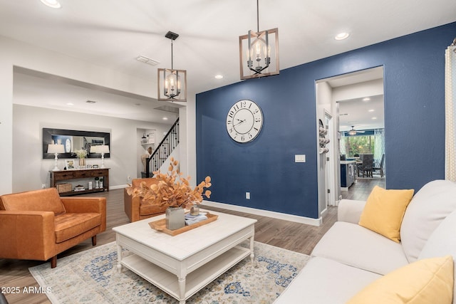 living area with stairs, wood finished floors, visible vents, and baseboards