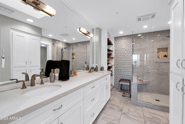 bathroom featuring marble finish floor, a shower stall, visible vents, and a sink