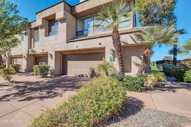 view of property featuring a garage, driveway, and stucco siding