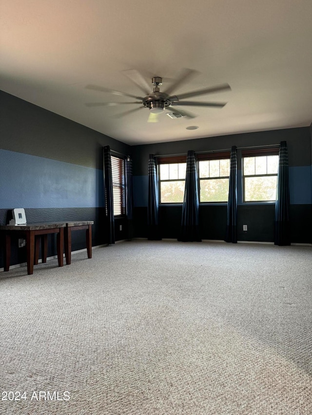 empty room with a wealth of natural light, carpet flooring, and ceiling fan