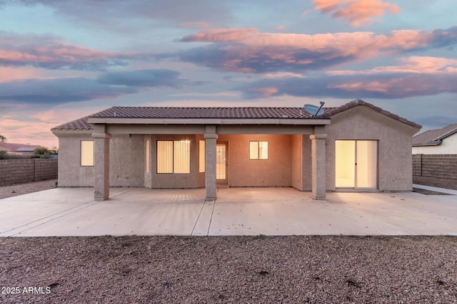 8271 W Cypress Point Cir, Arizona City, AZ 85123 - back of house at dusk featuring a tile roof, stucco siding, and a patio area