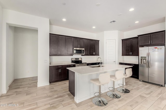3842 E Bartlett Way, Chandler, AZ 85249 - kitchen with stainless steel appliances, a sink, light wood-type flooring, a kitchen bar, and light countertops