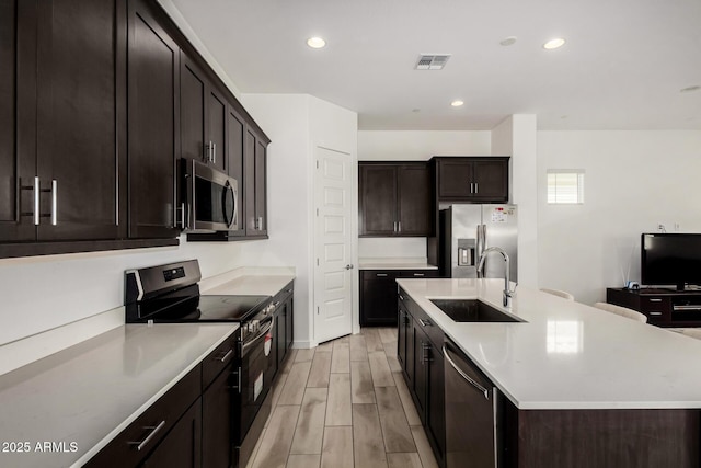 3842 E Bartlett Way, Chandler, AZ 85249 - kitchen featuring stainless steel appliances, a sink, wood tiled floors, light countertops, and an island with sink