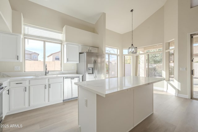 kitchen with a center island, white cabinets, sink, appliances with stainless steel finishes, and decorative light fixtures