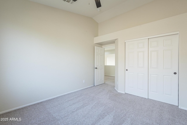 unfurnished bedroom featuring light carpet, vaulted ceiling, a closet, and ceiling fan