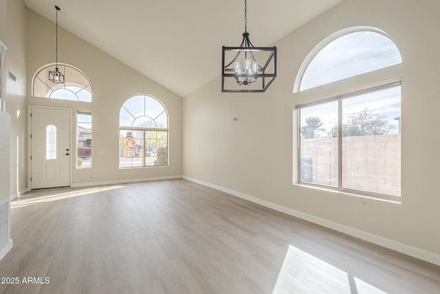 interior space with light hardwood / wood-style flooring, high vaulted ceiling, and an inviting chandelier