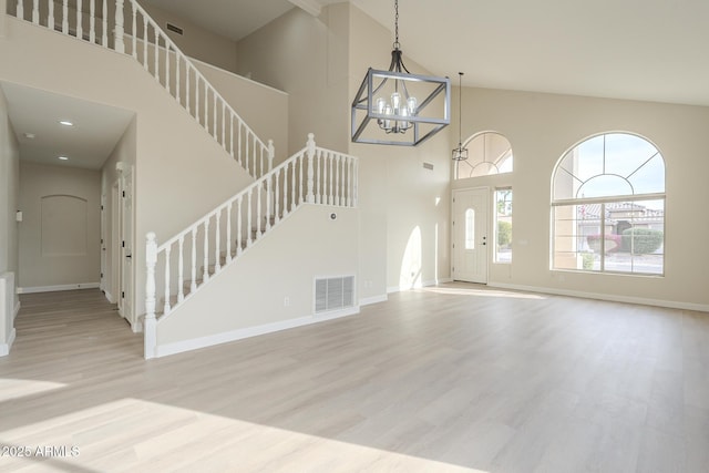 foyer entrance with a chandelier, a towering ceiling, and light hardwood / wood-style floors