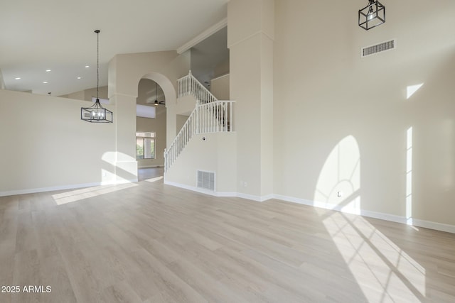 unfurnished living room with ceiling fan, light hardwood / wood-style flooring, and a towering ceiling