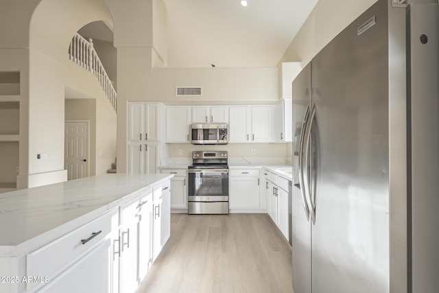 kitchen with light stone countertops, a center island, white cabinets, and appliances with stainless steel finishes