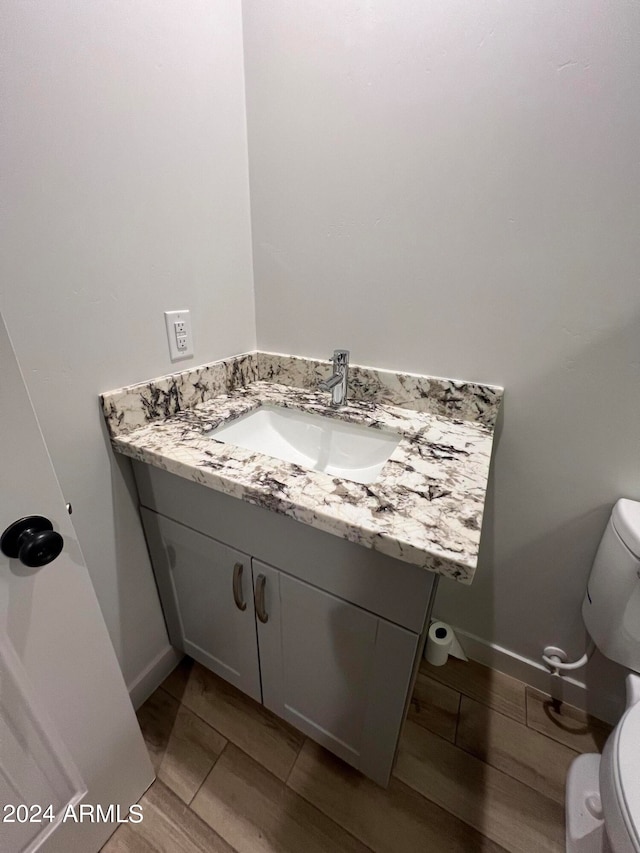 bathroom with hardwood / wood-style flooring, vanity, and toilet