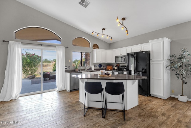 20239 N 39th Dr, Glendale, AZ 85308 - kitchen with black appliances, dark countertops, white cabinetry, a kitchen island, and wood-type flooring